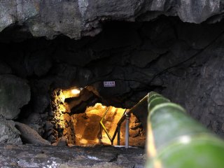 The entrance to the cave has a warning sign and some slippery stairs made of natural rocks.