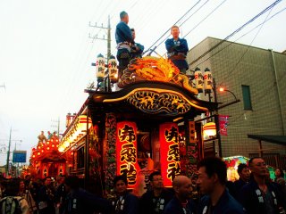 A large group of team members help pull the yatai to the battle area.