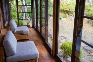 The engawa has lounge chairs facing a wall of windows bringing in the colors of the 300-year-old garden