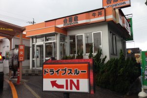 Yoshinoya&#39;s many restaurants are trimmed in orange and white with its name in kanji and English written in black