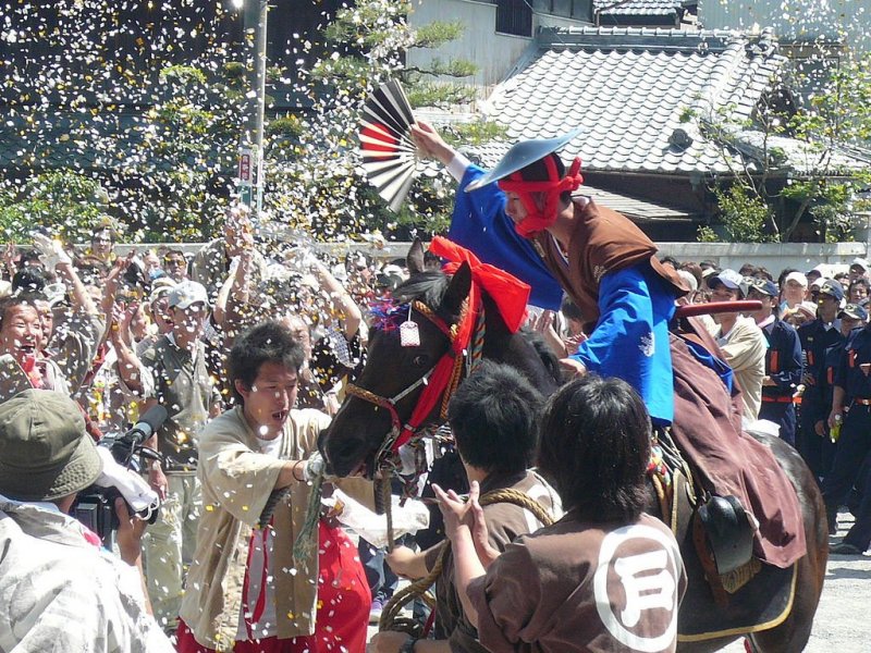 Riders push their horses to jump an earthen wall.