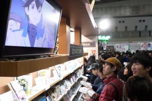 Attendees read manga and watch anime at AnimeJapan 2014.