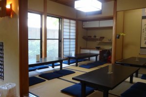 The back room with small tables on tatami floor looking out into an outside garden