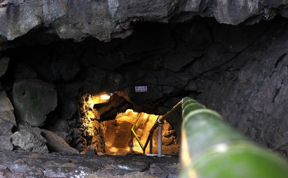 Lối vào hang động có dấu hiệu cảnh báo và một số cầu thang trơn trượt từ đá tự nhiên.