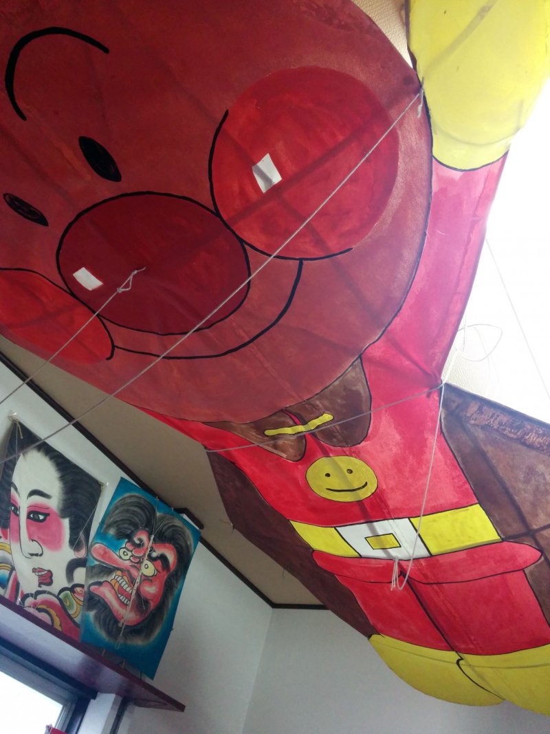 <p>An Anpanman character hovers over the workbench at the Kesennuma&nbsp;kite club&#39;s storage building</p>