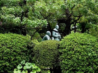 Statues of Yamazaki whiskey Distillery&#39;s founders stand in the well manicured garden