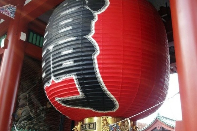 A giant red light which has Kanji, Japanese character, written "Kaminarimon" which means the lightning gate.