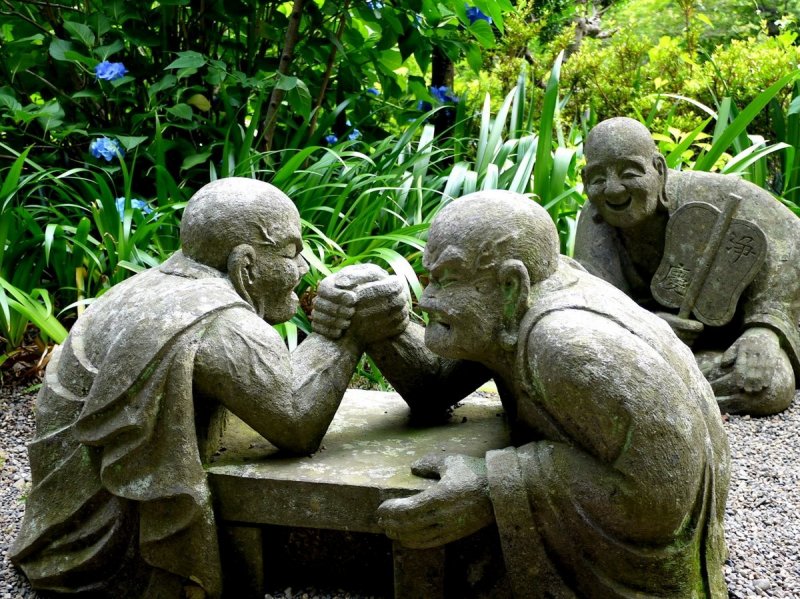 <p>Statues of monks holding an arm wrestling match</p>