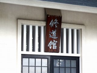 The signage says, Shudo-kan. The building turned out to be some kind of Budo-kan, a place where people practice Japanese martial arts such as Judo, Kendo, Kyu-do (archery), Naginata, etc.
