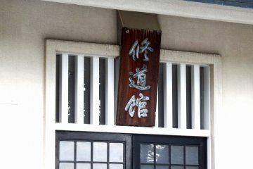 표지판에는 '슈도칸'이라고 쓰여 있다. 그 건물은 일종의 부도칸인 것으로 밝혀졌다. 부도칸은 유도, 켄도, 규도, 나기나타 등 일본 무술들을 행하는 곳이다