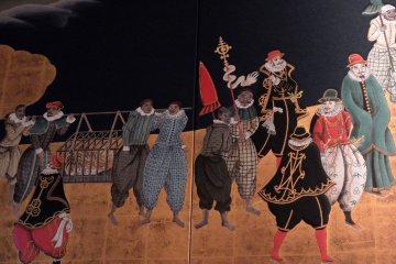 <p>Close-up of part of the Namban Screen. Western missionaries and a tiger in a cage can be seen</p>