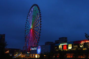 The 115 meter high Ferris Wheel outside Venus Fort, lit up against the night sky. A complete revolution of the wheel takes about 15 minutes, and offers views of Odaiba and the Tokyo Bay.
