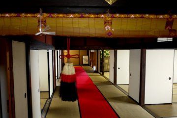 <p>Wide corridor with red carpet between the guest rooms</p>