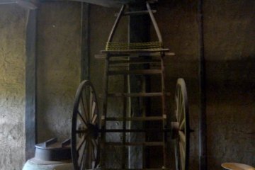 <p>A wagon is propped against a post next to a cooking stove</p>