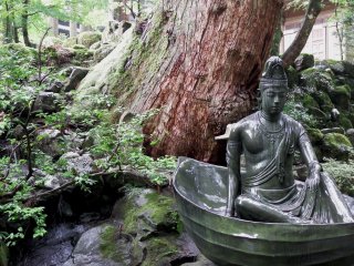 Statue of Goddess of Mercy sits in a boat in a small pond in front of the entrance gate
