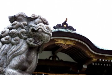 <p>Stone guardian lion and the shrine roof under a cloudy sky</p>