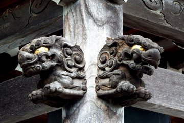 <p>Guardian dogs on the wooden pillar of the temple building</p>