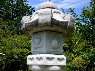 Hearts and a teapot decorate this stone lantern... could it be it an Alice in Wonderland theme?