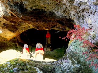 Statues with red aprons in the entrance to one of the caves
