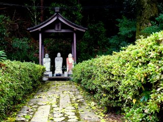 Three small statues at the end of a small, rough path