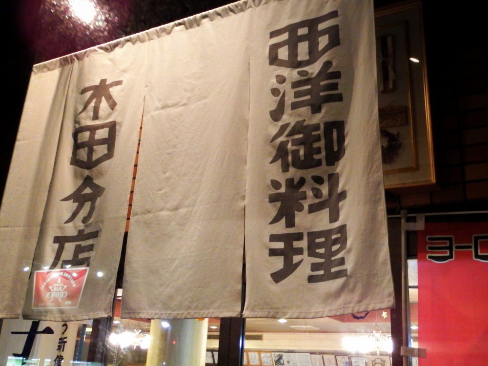 Rèm Noren treo ở lối vào của Europe-Ken ở Fukui đọc là, 'Ẩm thực phương Tây'