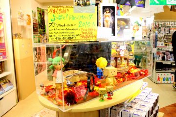 <p>Anime figure toys are all over the place. Some are in glass display cases while others are on the shelves.</p>