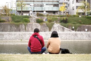 <p>People sitting by the riverbank</p>