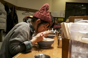 <p>Eating ramen can be a ritual. This customer seems to be enjoying her food</p>