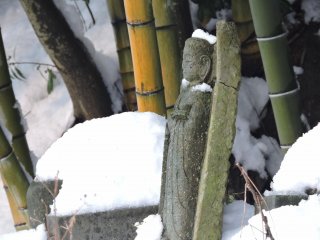 Broken Jizo statue standing forlornly in a Jizo cemetery covered with snow