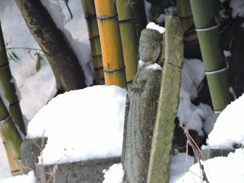 รูปปั้นจิโซะที่มีรอยแตกยืนอยู่ท่ามกลางหิมะในสุสานจิโซะ