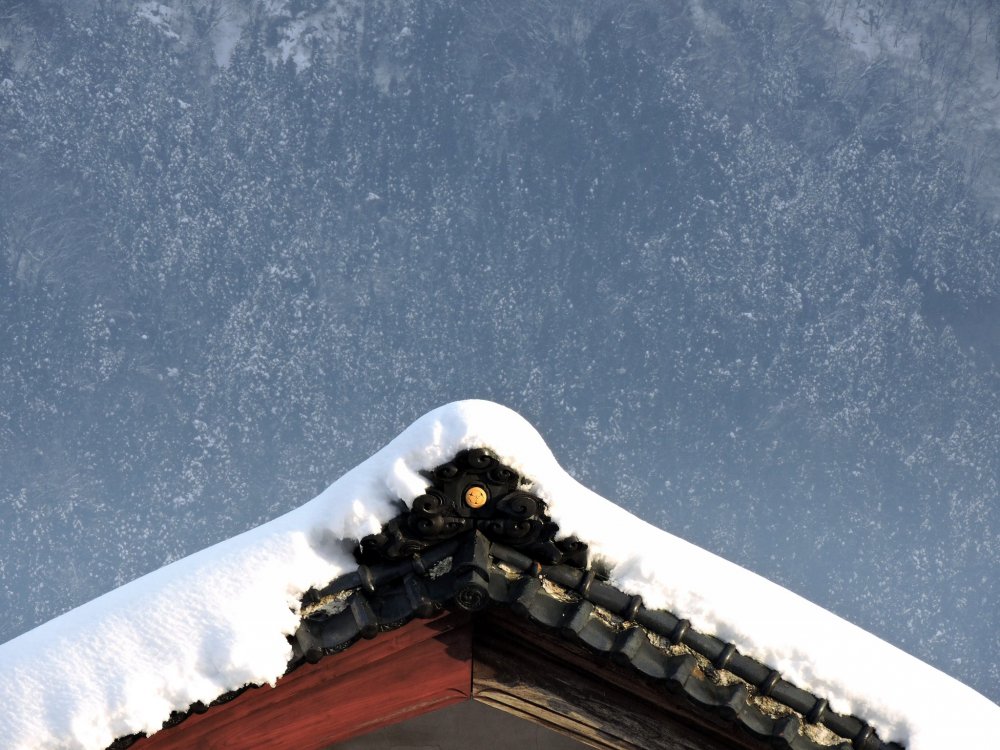 Украшенная снегами крыша дома на фоне таинственных гор