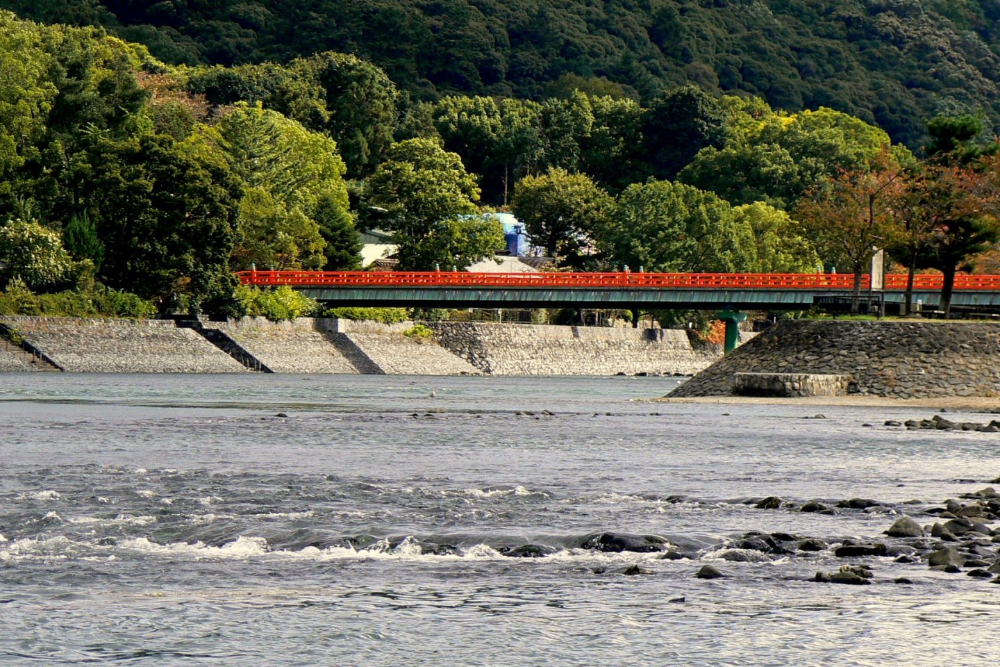 A red pedestrian bridge spans the river