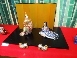 A small pair of dogs accompanies this traditional Hina couple