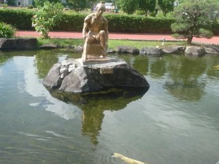Pond with statue and several gold koi fish.