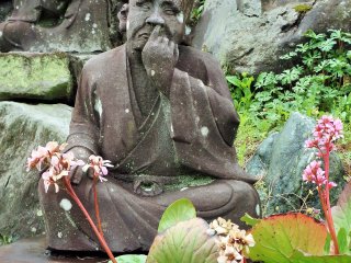 Why is this statue picking his nose and the one behind him drinking heavily? A third (just out of the frame) is eating mitarashi dango, a traditional Japanese dessert. Hmmm.