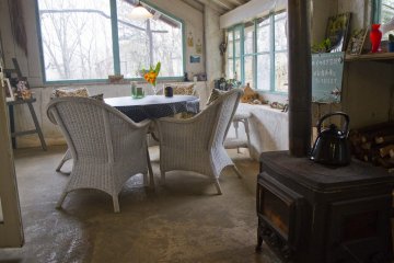<p>The sunroom is heated with a woodburning stove in winter and looks out into the gardens</p>