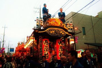 <p>A large group of team members help pull the yatai to the battle area.</p>