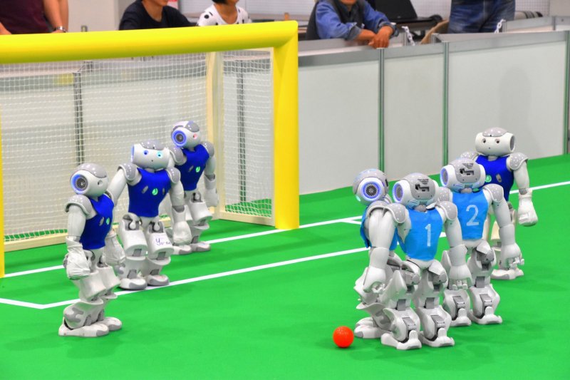 <p>Autonomous humanoids playing soccer. The humanoids wearing deep-blue uniforms belong to Crude from Taiwan, and the ones wearing sky-blue uniforms are JoiTech of Osaka University.</p>