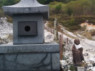 Jizo with a bib next to a stone lantern