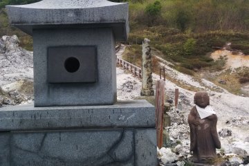 <p>Jizo with a bib next to a stone lantern</p>