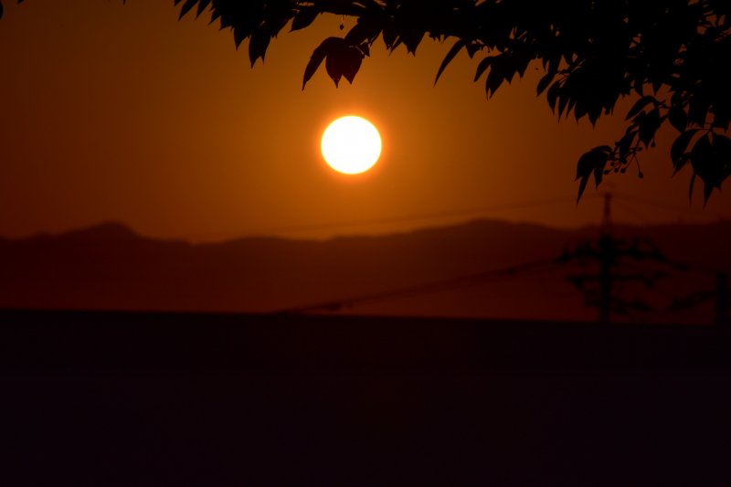 <p>The huge round-shaped sun setting over a mountain</p>