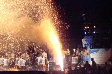 The hand-held fireworks light the taiko drums behind
