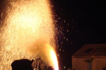 Fireworks spray from a bamboo tube during the Summer Festival