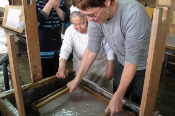 The women at the Ikazaki workshop can show you how to make your own sheet. The first step is the hardest: the pulp must be evenly spread over the screen. The women handle the heavy screens with skill and dexterity.