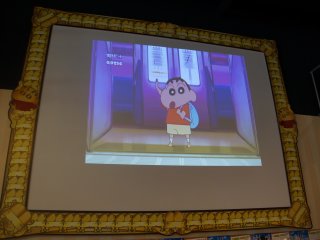 A large screen playing Crayon Shin-chan episodes and promoting the most recent movie greets visitors at the entrance. A very appropriate design frames the screen.&nbsp;