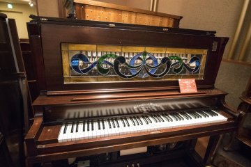 <p>This is no piano. Behind the panel lies the musical box which not only plays the tunes, but also engages the keyboards, making it look like the &#39;piano&#39; is being performed on.</p>