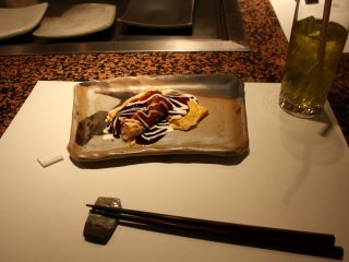 Afterwards, the chef adds some Okonomiyaki sauce (the taste is sweet and very delicious) and mayonnaise, just like for the Okonomiyaki
