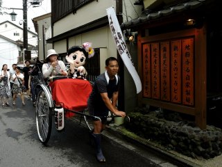 Kusatsu Onsen&#39;s mascot, Yumomi-chan, accompanies a tourist on a rickshaw ride &nbsp;
