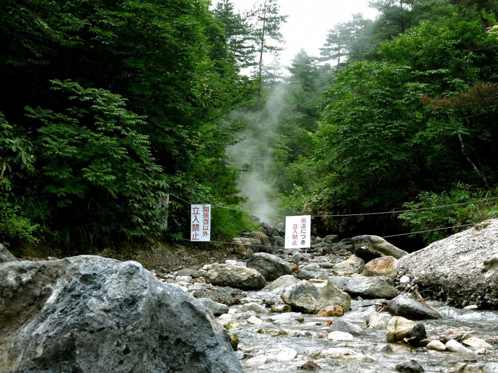 Steam rises from the water behind a rope and 'Keep Out' signs
