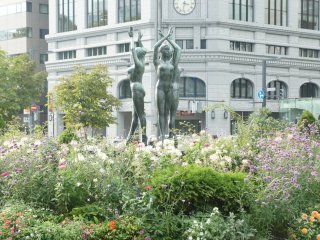 Tak mengira ini Jepang ya? Bunga-bunga cantik, patung penari, dengan latar bangunan khas Eropa di Taman Oodori.